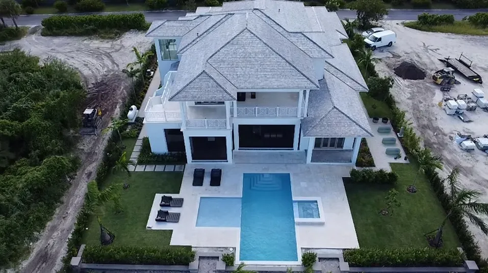 Aerial view of a two storey white residence with a rectangular swimming pool and spa in the garden