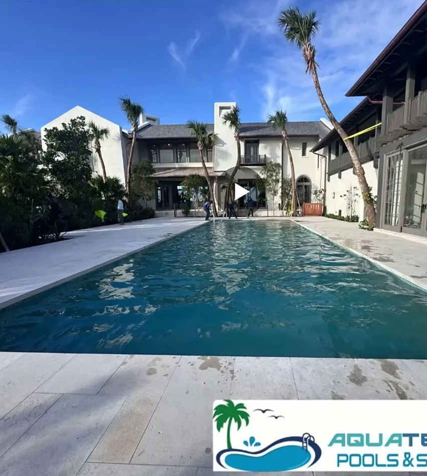 Swimming pool beside a tall colonial style building with palm trees and a clear blue sky