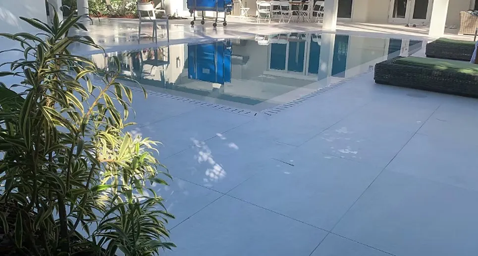 Pool deck with glass railing, paved surround and outdoor lounge seating at a modern property